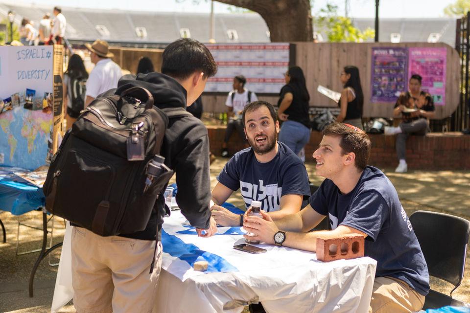 People speaking to passerby at a booth